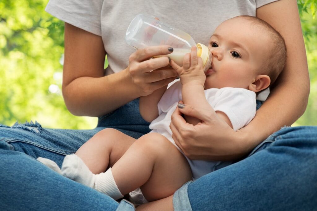 Woman feeding milk to baby in a bottle