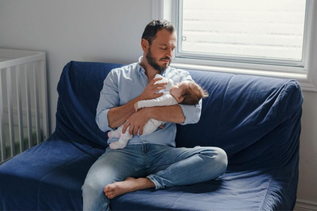 Father feeding newborn with bottled milk