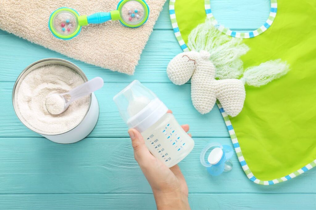 Person holding feeding bottle of baby milk formula