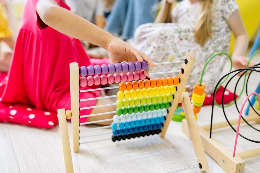 A baby playing with a wooden abacus trying to learn maths