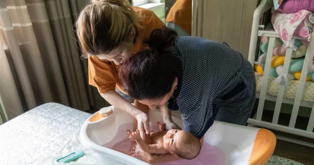 Essential Newborn Bathing Tips For Parents 2 Mother and grandmother bathing newborn baby in a baby bath
